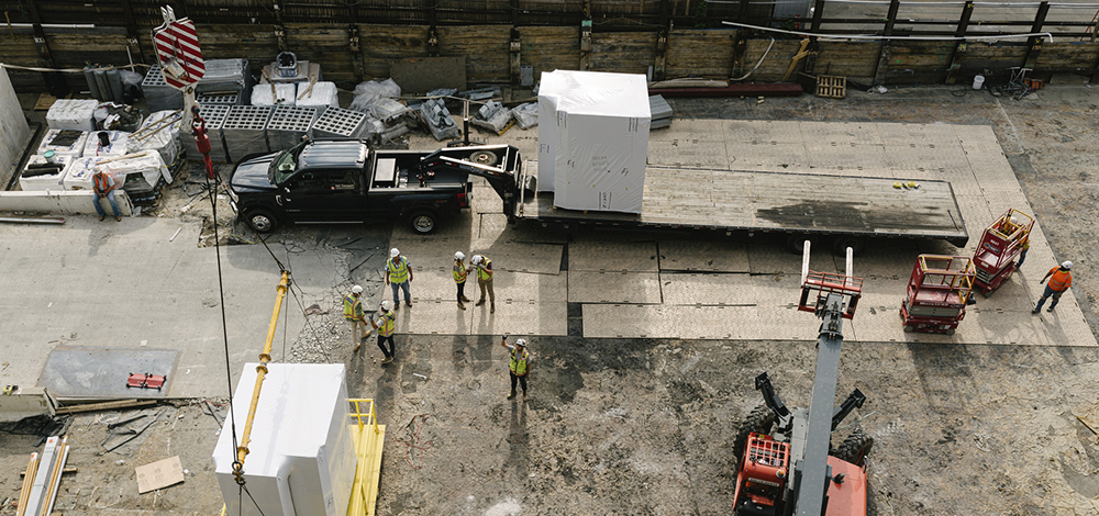 Bathroom pods are unloaded from one of 26 trucks arriving on the jobsite from Texas.